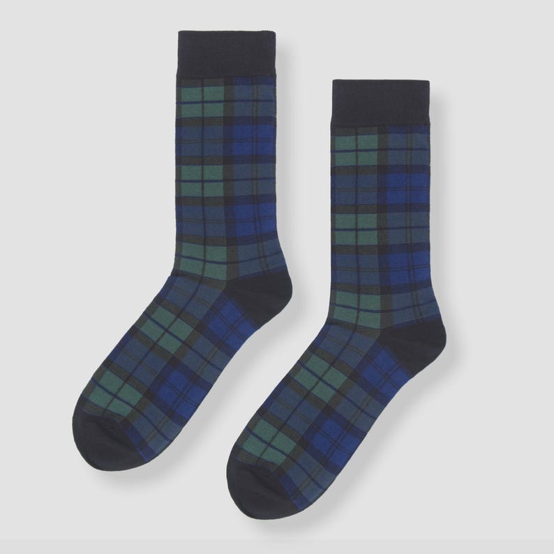 May include: A pair of crew-length socks featuring a dark blue, forest green, and black plaid tartan pattern. The socks have solid black cuffs at the top, solid black heels, and solid black toe sections, providing a consistent look for daily wear.