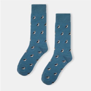 Puede incluir: Un par de calcetines azules con un patrón de frailecillo blanco y marrón.