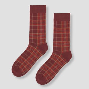 May include: Two burgundy socks featuring a plaid design in red and tan. The socks have solid burgundy cuffs, heels, and toes. These socks are a fashionable accessory for any outfit.