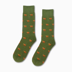 Peut inclure: Une paire de chaussettes vertes avec un motif répété de vaches orange.