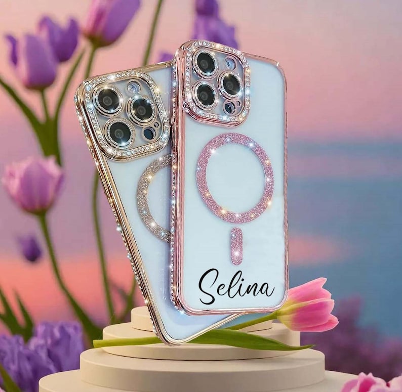 Op de afbeelding: Twee witte iPhone-hoesjes met een ros&eacute;gouden rand en een glinsterende roze ringhouder. Het hoesje bovenaan heeft de naam "Selina" erop.