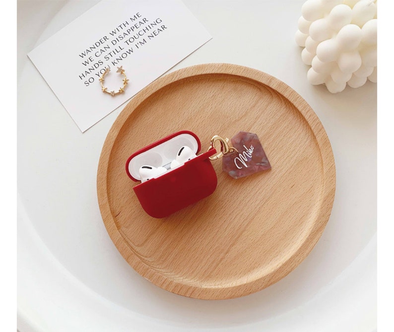 May include: Red Airpods case with a pink and white marbled keychain that says "Miko".