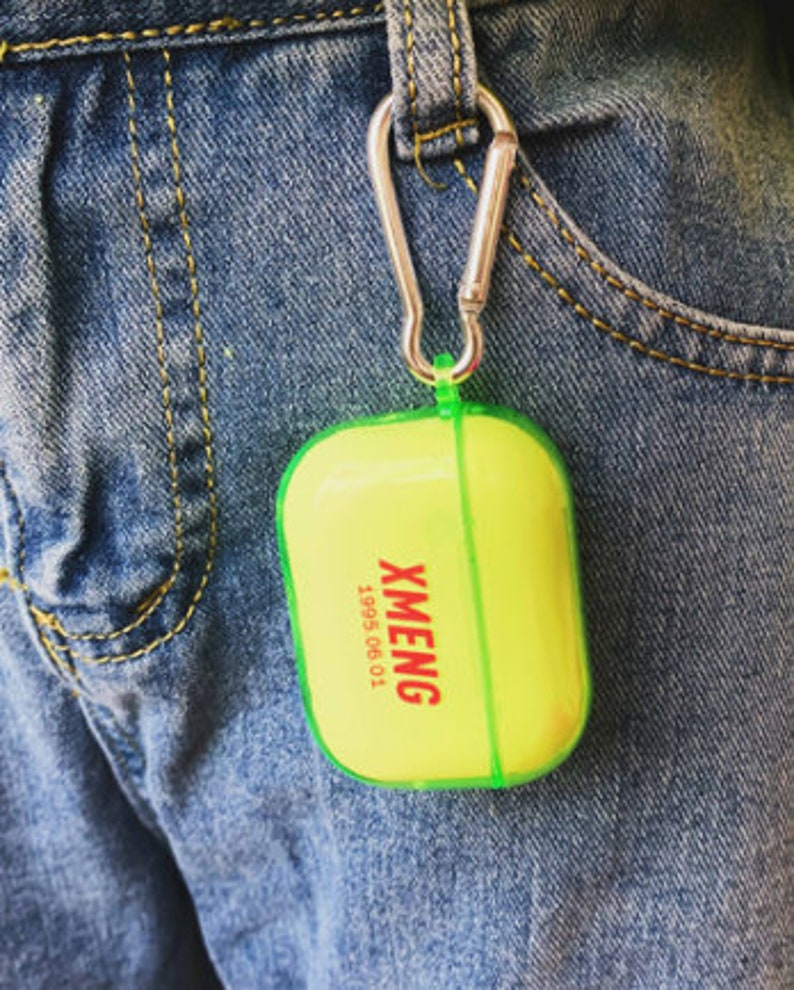 K&ouml;nnte beinhalten: Ein leuchtend gelbes und gr&uuml;nes Etui mit einem silbernen Karabinerhaken. Auf dem Etui steht der Text "XMENG 1995 06 01".