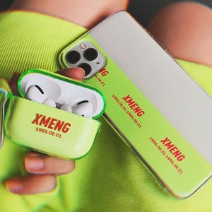 K&ouml;nnte beinhalten: Eine transparente Handyh&uuml;lle mit gr&uuml;nem und wei&szlig;em Design. Die H&uuml;lle tr&auml;gt den Text "XMENG 1995.06.01". Die H&uuml;lle wird mit einer passenden gr&uuml;nen und wei&szlig;en AirPod-H&uuml;lle gezeigt.