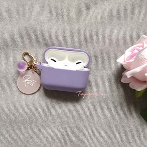 May include: A purple silicone case for wireless earbuds with a gold chain and a charm that says "Kelli".