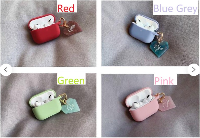 May include: Four Airpods cases with charms. The cases are red, blue-grey, green, and pink. Each case has a heart-shaped charm with a different color and inscription.