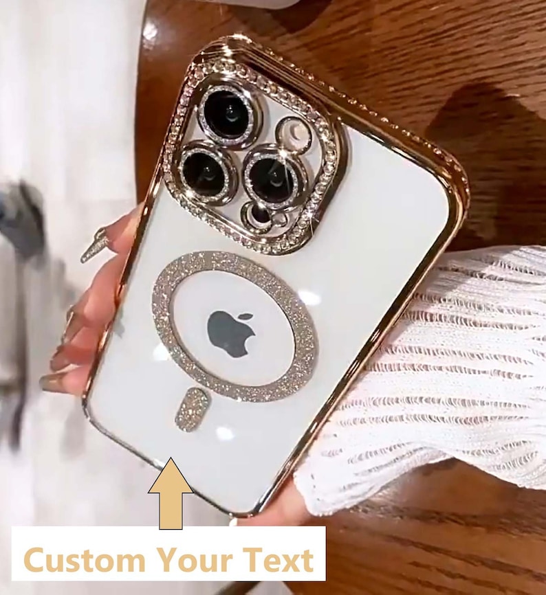 Op de afbeelding: Witte iPhone-hoes met een gouden rand en een met diamanten bezet ontwerp. De hoes heeft een ring aan de achterkant om de telefoon vast te houden. De tekst "Custom Your Text" staat onderaan de afbeelding.