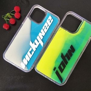 Puede incluir: Dos fundas transparentes para teléfono con líquido en su interior. Una funda es azul y dice "nickynee" y la otra funda es amarilla y dice "john".