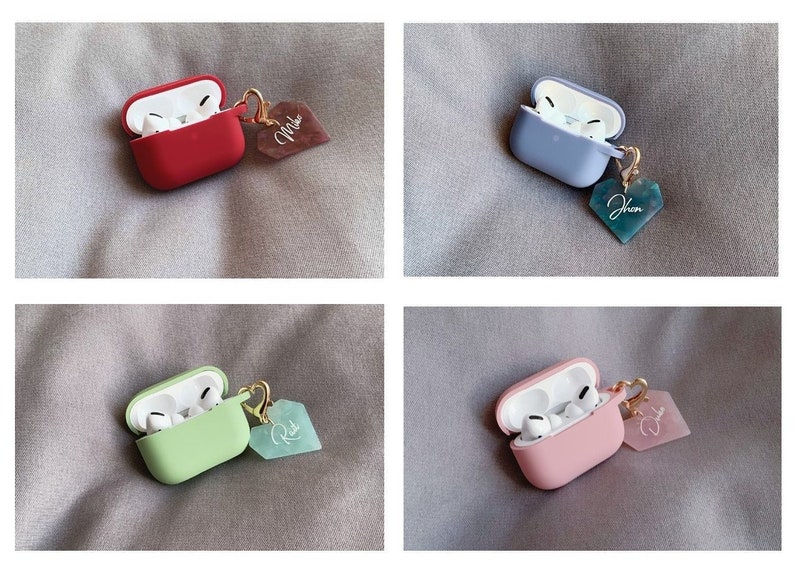 May include: Four Airpods cases with different colored silicone covers and heart-shaped charms. The charms are personalized with the names "Mike", "Jhon", "Rik", and "Dhon".