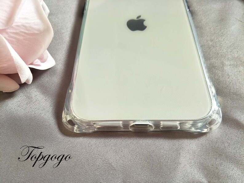 May include: A clear phone case with a raised edge around the screen and camera. The case is designed to fit a smartphone with a large screen and a single camera lens. The case is made of a clear, flexible material that is designed to protect the phone from scratches and bumps.