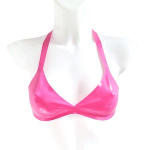 May include: A bright pink latex halter top featuring a triangular cup design with a smooth, glossy finish. The garment has a single strap that loops around the neck and a band that secures around the torso, showcasing a vibrant, solid color.