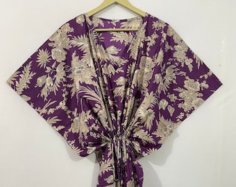 May include: A purple and cream floral print kaftan with a V-neck and short sleeves.
