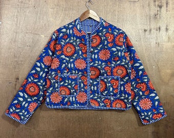 May include: A blue quilted jacket with a floral print featuring orange and white flowers. The jacket has a zip closure and two pockets.