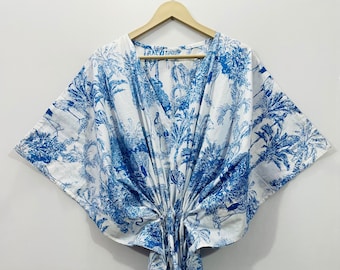 Peut inclure: Un kimono à motifs blancs et bleus avec un col en V et des manches courtes. Le motif représente des palmiers et des oiseaux.