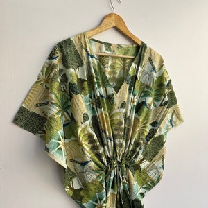 May include: A green and white kaftan with a peacock print. The kaftan has a V-neck and a drawstring waist.