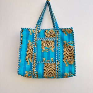 May include: A blue and orange tote bag with a tiger print. The bag has a zippered pocket on the front and two handles.