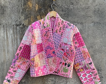 May include: A pink quilted jacket with a floral print. The jacket is made of patchwork fabric and has a long sleeve.
