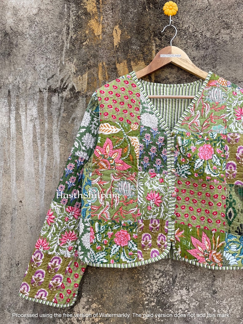 May include: A green quilted jacket with a patchwork design featuring floral patterns in shades of pink, green, and white. The jacket has a V-neck and a button closure. The text "Hasthshilpam" is visible on the jacket.