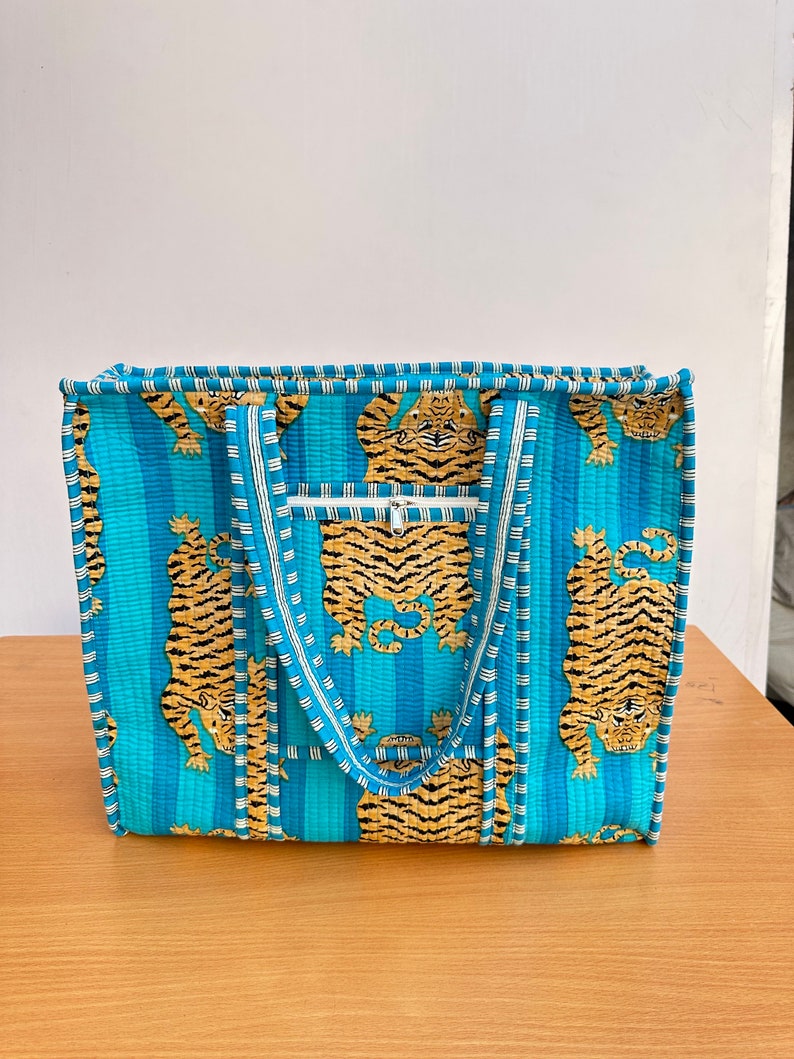 May include: A blue and white striped tote bag with a tiger print. The bag has two handles and a zippered pocket on the front.