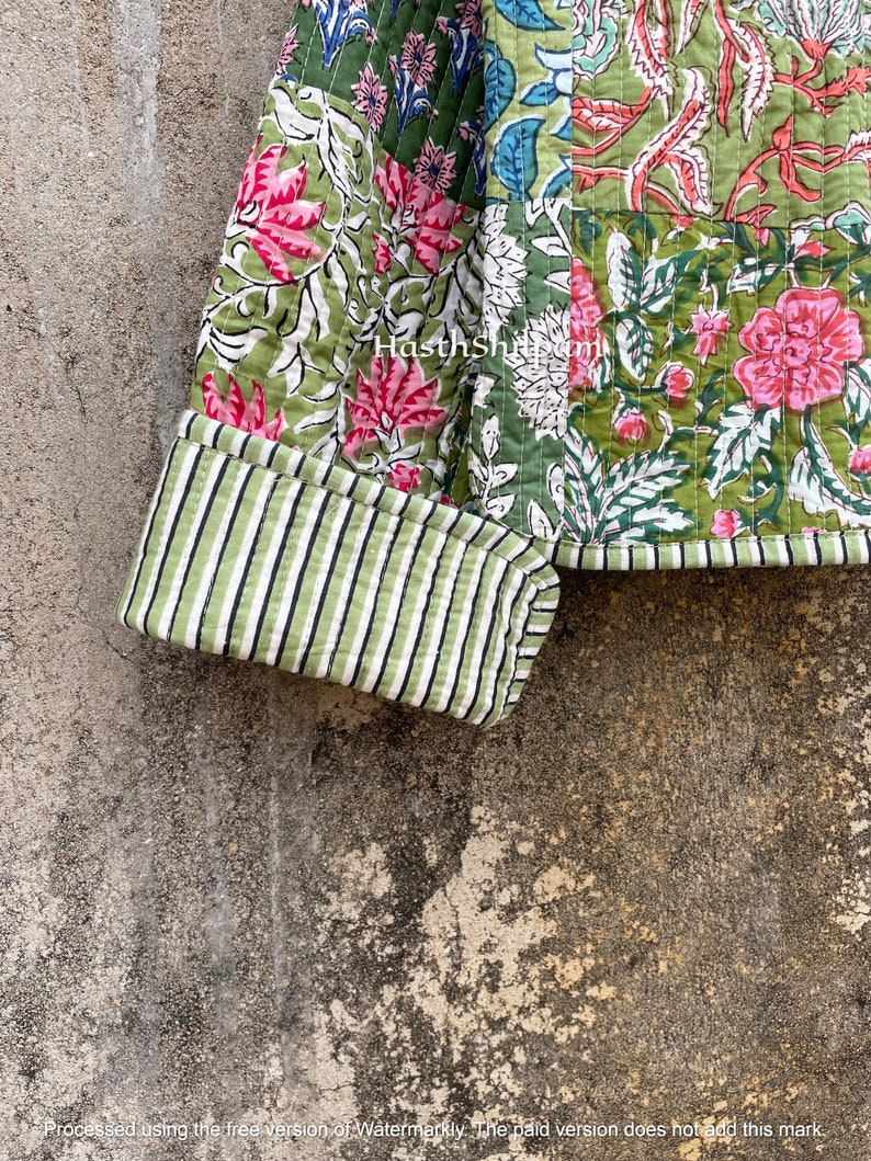 May include: A green and pink patchwork quilt with a floral print. The quilt has a striped green and white cuff. The quilt is made of cotton fabric.