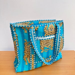 May include: A blue and white striped tote bag with a tiger print. The bag has two handles and a zipper closure.