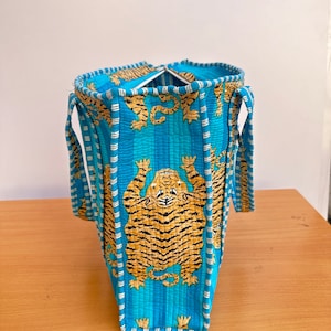 May include: A blue tote bag with white stripes and a tiger print. The bag has two handles and a zipper closure.