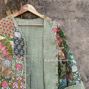 May include: A green quilted jacket with a floral print. The jacket has a striped lining and a button closure. The text "Hasthshilpam" is visible on the jacket.
