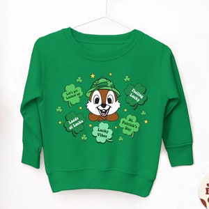 Puede incluir: Sudadera verde de manga larga con un chipmunk de dibujos animados que lleva un sombrero verde y un diseño de trébol. El texto en la sudadera dice "Let's get locked up", "Loads of Lucks", "Feeling Lucky", "Lucky Vibes" y "St. Patrick's Day".