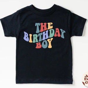 K&ouml;nnte beinhalten: Schwarzes T-Shirt mit dem Text "The Birthday Boy" in Regenbogenfarben.