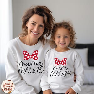May include: White sweatshirts with red and white polka dot bows and the text "mama mouse" and "mini mouse" printed on them. The sweatshirts are worn by a woman and a young girl.