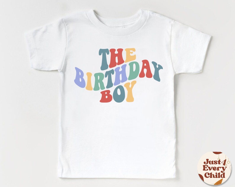K&ouml;nnte beinhalten: Wei&szlig;es T-Shirt mit dem Text "The Birthday Boy" in Regenbogenfarben.