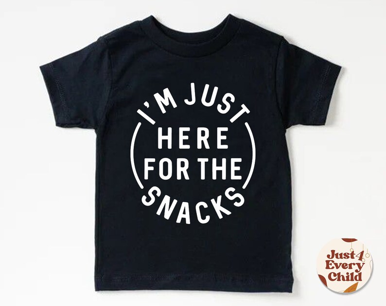 May include: Black short-sleeved t-shirt with white text that reads "I'm Just Here For The Snacks" in a circle.