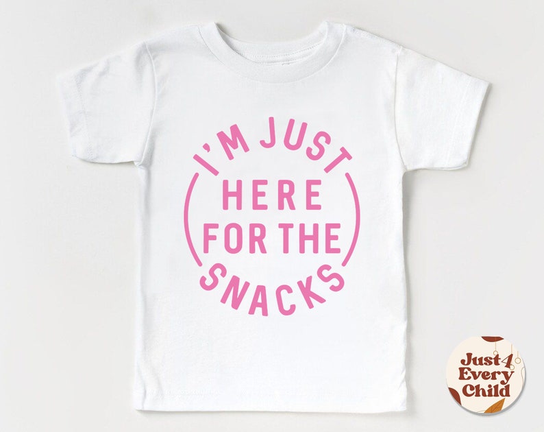May include: White t-shirt with pink text that reads "I'm Just Here For The Snacks" in a circle.