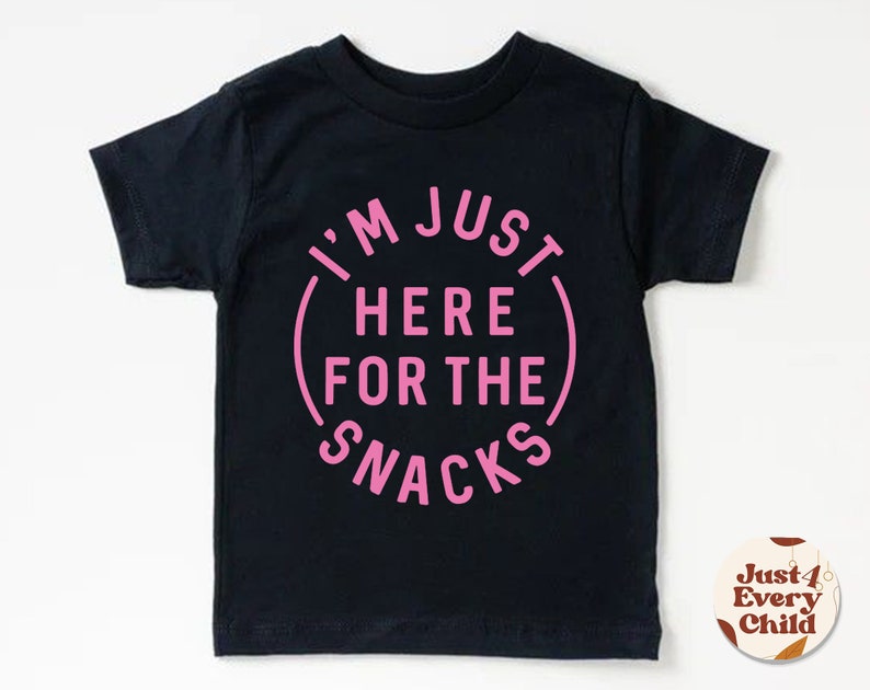 May include: Black short-sleeved t-shirt with pink text that reads "I'm Just Here For The Snacks".