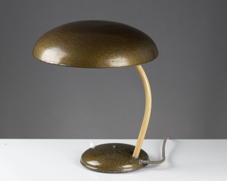 May include: A green desk lamp with a curved, cream-colored arm and a round, textured shade.