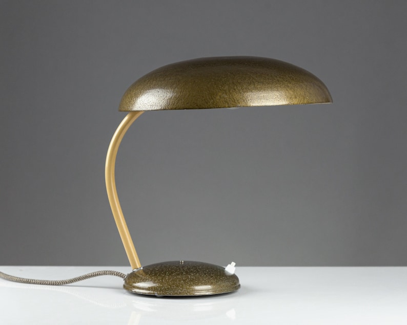 May include: A vintage gold-colored desk lamp with a curved wooden arm and a round, textured shade.