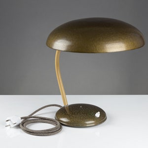 May include: A vintage green desk lamp with a mushroom-shaped shade and a wooden arm. The lamp has a white cord and plug.