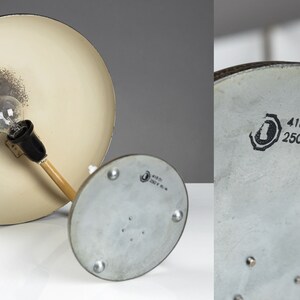 May include: A vintage desk lamp with a white metal shade and a wooden arm. The lamp has a silver base with a label that reads "418 01 250 V 60 W".