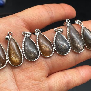 May include: Seven teardrop-shaped pendants with a silver-toned metal setting. The pendants are made of a dark brown stone with a shimmery, iridescent finish.