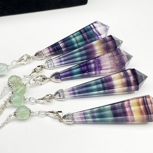 May include: Five silver chains with fluorite crystal pendants. Each pendant is a double-terminated point with a rainbow of colors, including purple, green, and yellow. The chains are adorned with green beads.