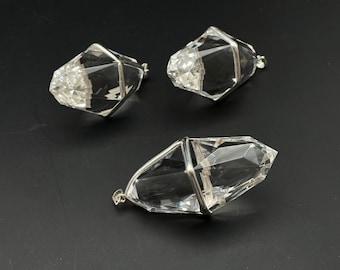 May include: Three clear quartz crystal pendants with silver wire cages. The crystals are faceted and have a pointed shape.