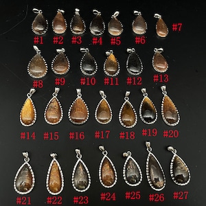 May include: Twenty-seven teardrop-shaped pendants with a silver bezel setting. The pendants are made of a brown and gold material with a shimmering effect. The pendants are numbered 1 through 27.