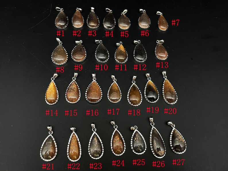 May include: Twenty-seven teardrop-shaped pendants with a silver bezel setting. The pendants are made of a brown and gold material with a shimmering effect. The pendants are numbered 1 through 27.