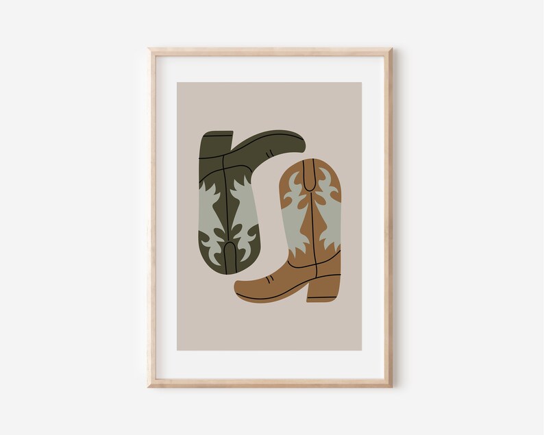 May include: A framed print of a minimalist illustration of two cowboy boots. One boot is brown with a light blue design and the other is green with a light blue design. The boots are on a light brown background.