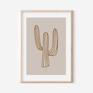 May include: A minimalist art print featuring a brown line drawing of a cactus on a light beige background. The print is framed in a light wood frame.