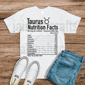 May include: White t-shirt with a black graphic of a Taurus zodiac sign and a nutrition facts label listing traits like loyal, patient, generous, persistent, stubborn, beauty, friendly, perseverance, determination, and dependable. The text "Taurus Nutrition Facts" is at the top of the graphic. The text "Servings per container: 1 Awesome Zodiac Sign" is below the title. The text "%Daily Value*" is to the right of the traits. The text "*DAILY VALUE MAY VARY" is at the bottom of the graphic.