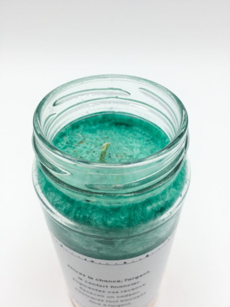 May include: A teal green candle in a glass jar with a white label that reads "Attracts luck, chance, forget, comfort, financial abundance, you can reverse the flow of events, opens a door to a new beginning".