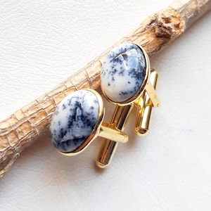 May include: A pair of gold cufflinks with oval-shaped white and black agate stones.