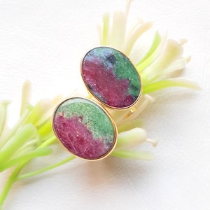 Puede incluir: Un par de pendientes ovalados con piedras preciosas verdes y rosas engastadas en oro.