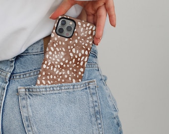 May include: A smartphone case featuring a brown background with a white speckled pattern. The case has a cutout for a triple-lens camera system and is partially inserted into the back pocket of a pair of light blue denim jeans.